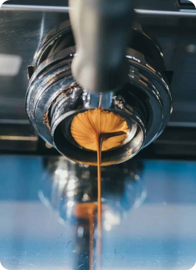 A close up shot of coffee pouring out of the machine at Brew Coffee Roasters